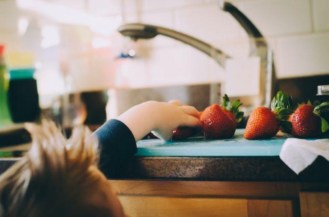 Enfant qui mange fraises près d'un évier